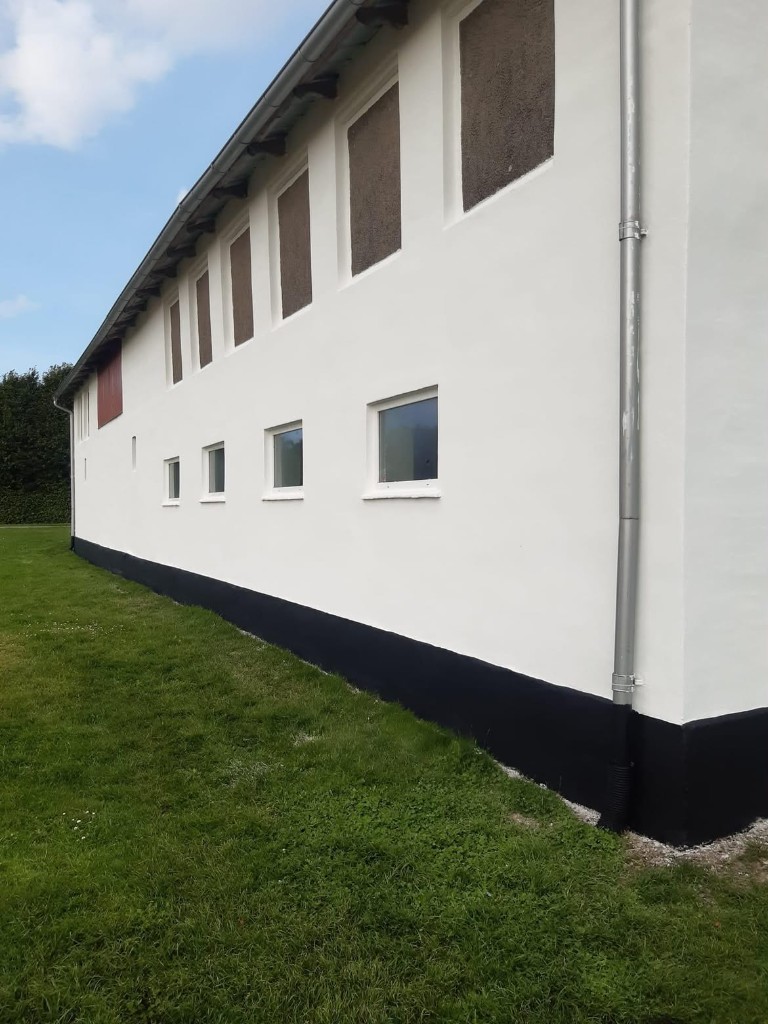 Hvidpudset facade med sort sokkel
